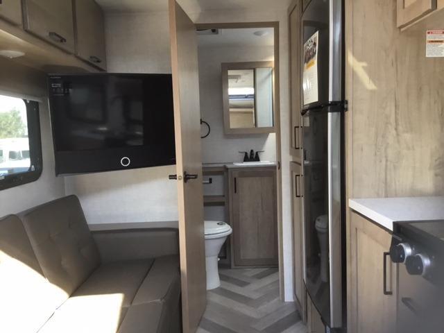 Interior view of the RV with a bathroom, living space and a kitchen.
