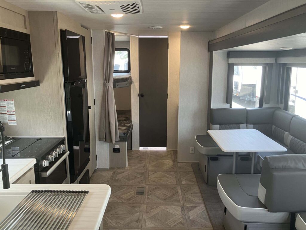 Interior view of the RV with a dinette, bedroom and a kitchen.