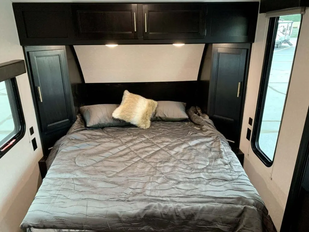 Bedroom with a queen size bed, overhead cabinets and shirt closets.