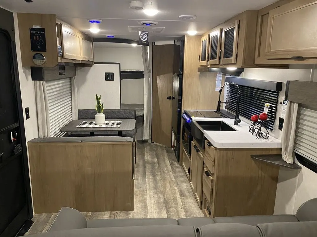 Interior view of the RV with a dinette, bedroom and a kitchen.