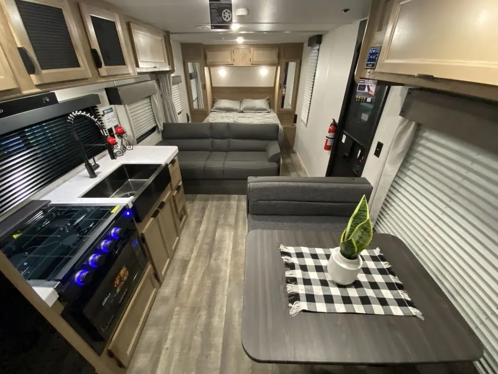 Interior view of the RV with a dinette, living space, bedroom and a kitchen.