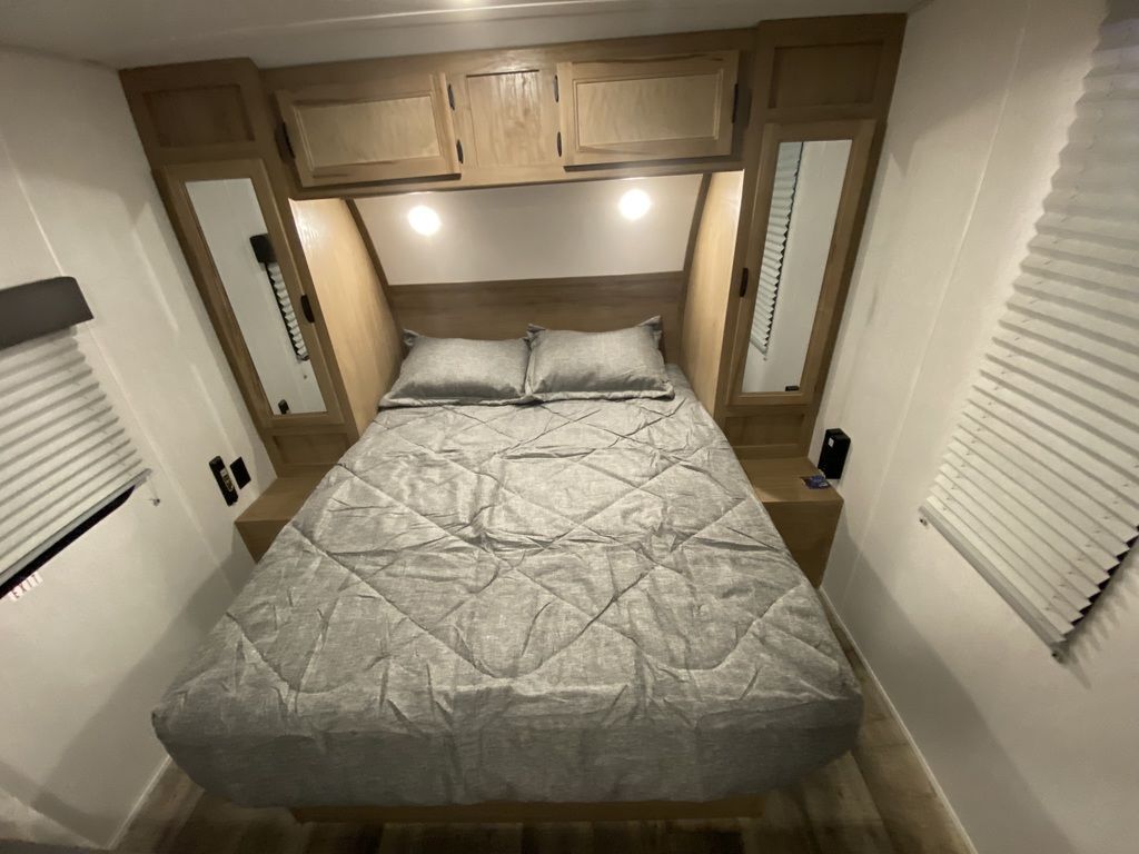 Bedroom with a queen size bed, overhead cabinets and shirt closets.