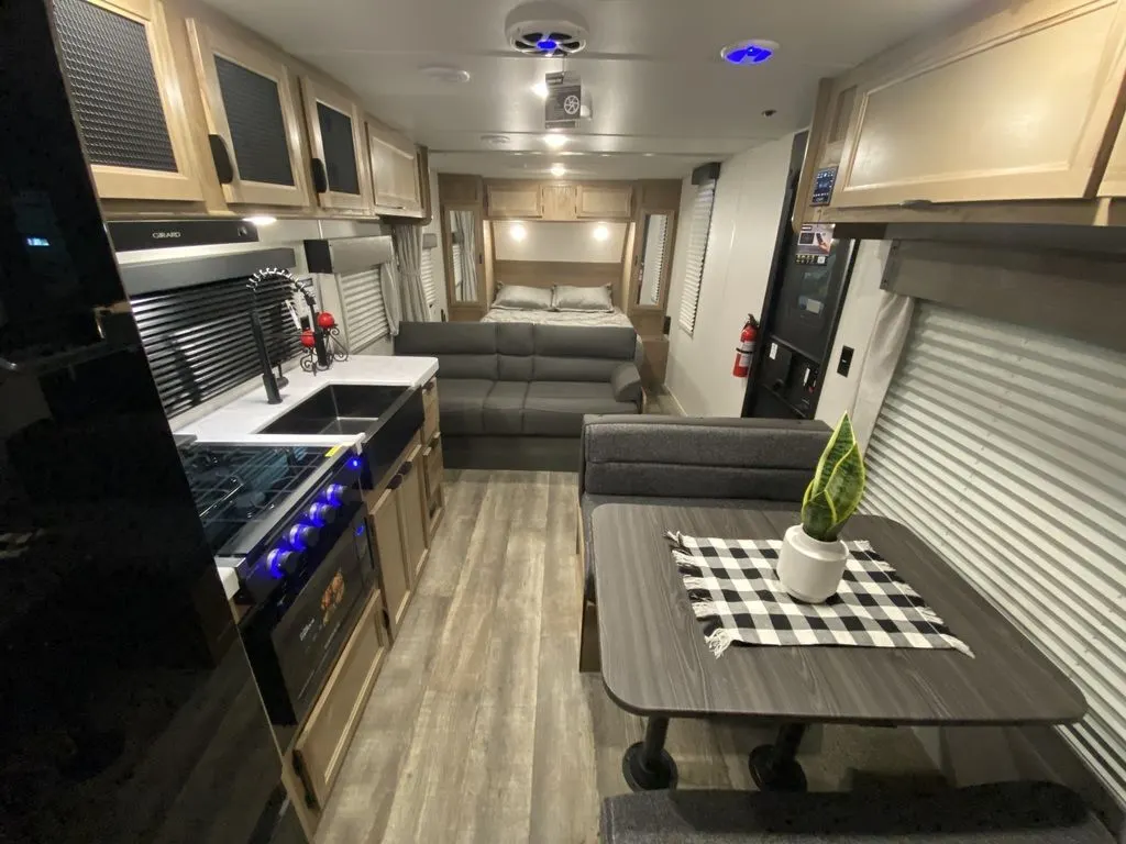 Interior view of the RV with a dinette, living space, bedroom and a kitchen.