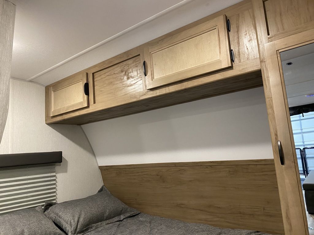 Bedroom with a queen size bed, overhead cabinets and shirt closets.