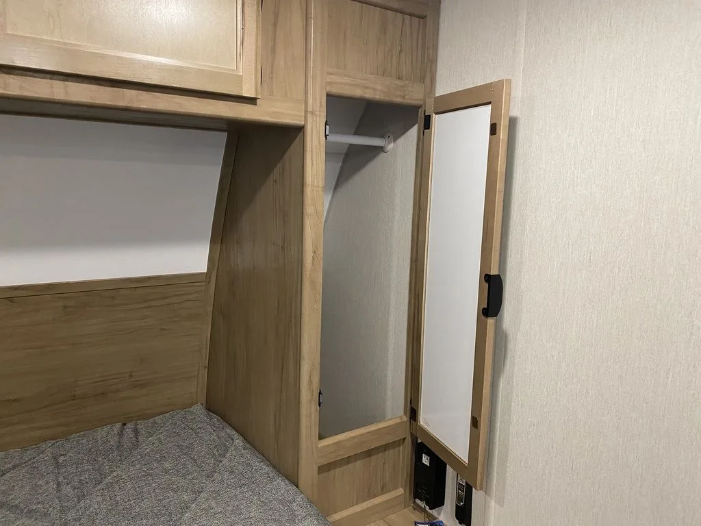 Bedroom with a queen size bed, overhead cabinets and shirt closets.