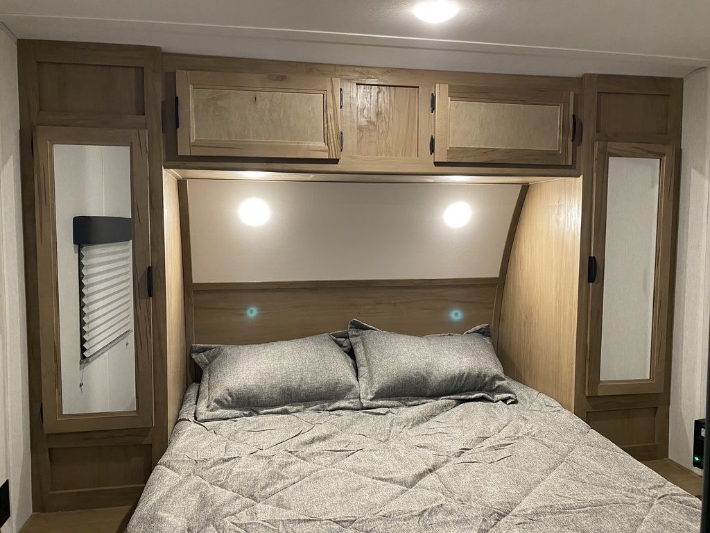 Bedroom with a queen size bed, overhead cabinets and shirt closets.