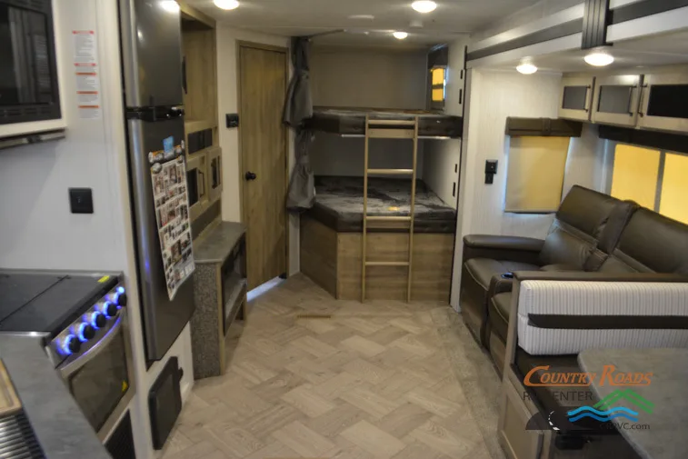 Interior view of the RV with a dinette, bedroom, living space and a kitchen.