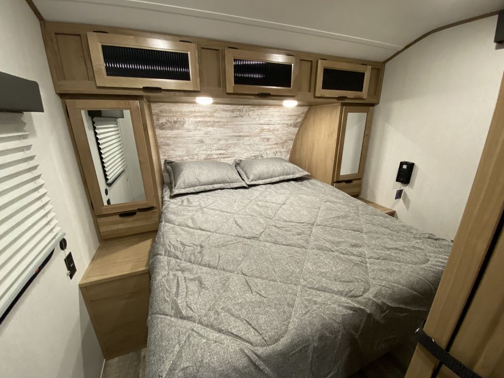 Bedroom with a queen size bed, overhead cabinets and shirt closets.