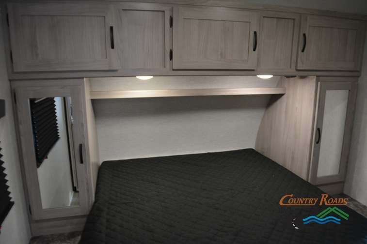 Bedroom with a queen size bed, overhead cabinets and shirt closets.