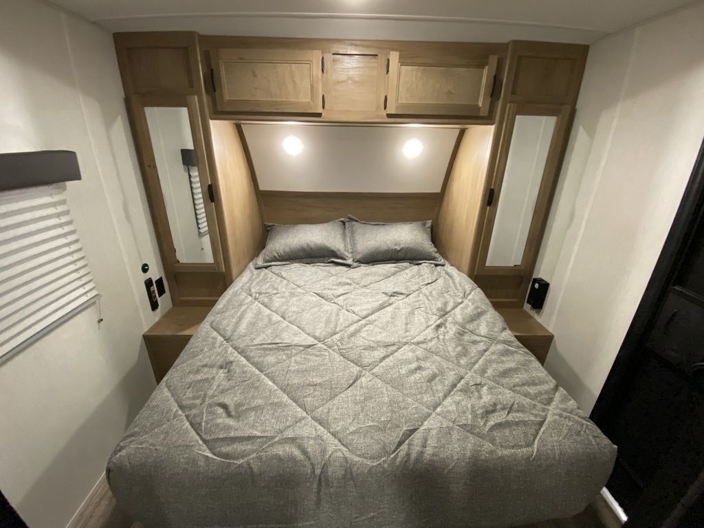 Bedroom with a queen size bed, overhead cabinets and shirt closets.