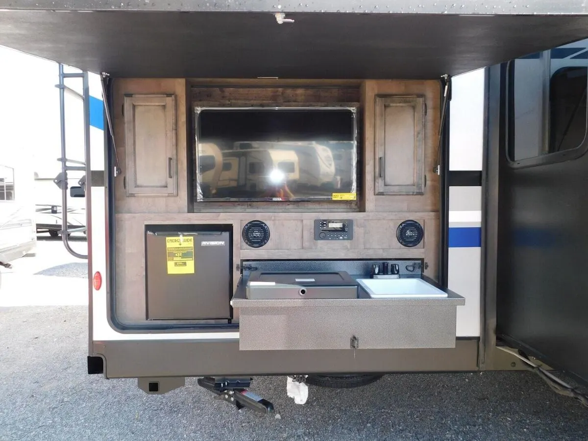 Outdoor kitchen with a gas griddle, TV and a fridge.