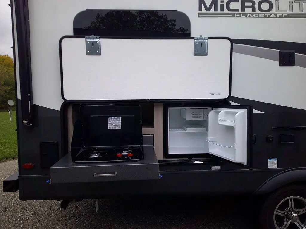 Outdoor kitchen with a gas griddle and a fridge.