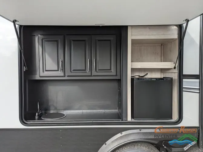 Outdoor kitchen with a sink, cabinets and a fridge.