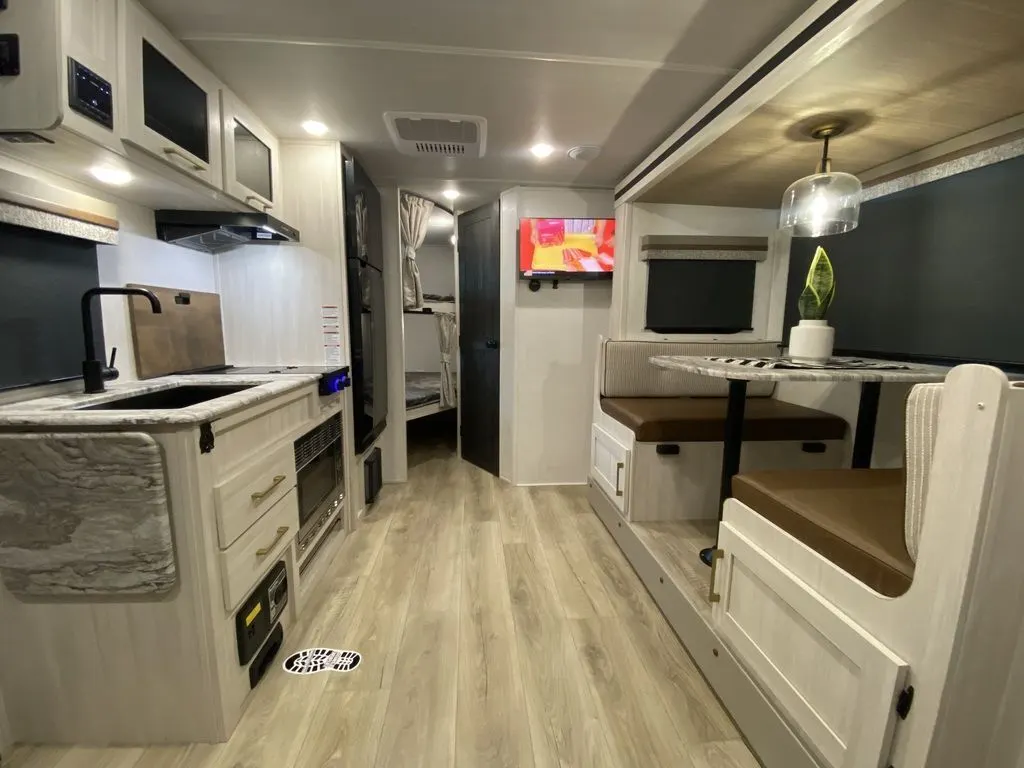 Interior view of the RV with a dinette, bedroom and a kitchen.