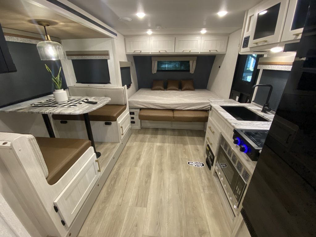 Interior view of the RV with a dinette, bedroom and a kitchen.