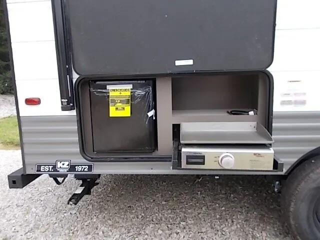 Outdoor kitchen with a gas griddle and a fridge.