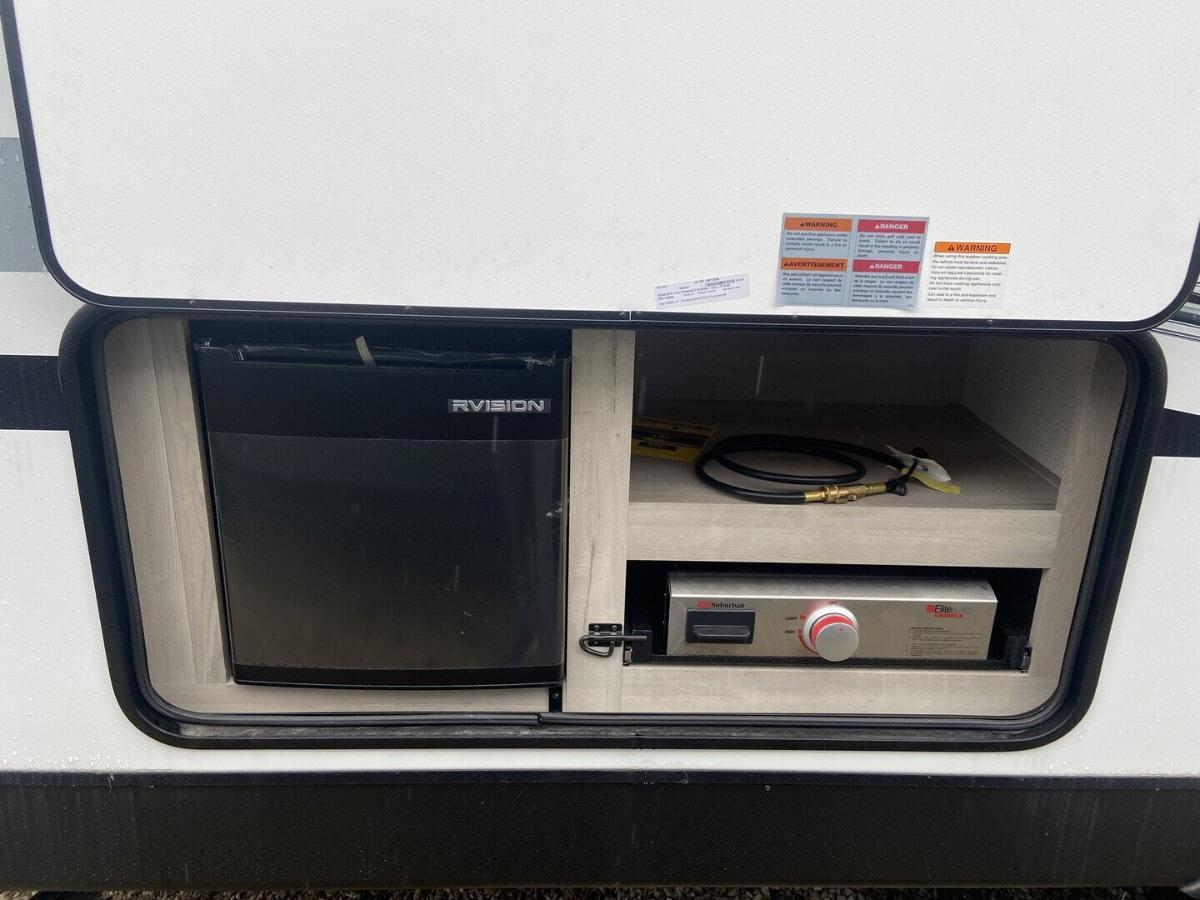 Outdoor kitchen with a gas griddle and a fridge.