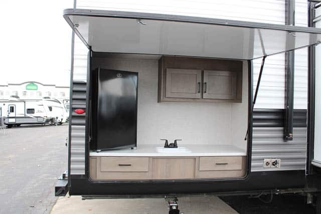 Outdoor kitchen with a sink, cabinets and a fridge.