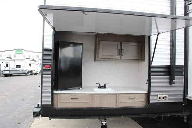 Outdoor kitchen with a sink, cabinets and a fridge.