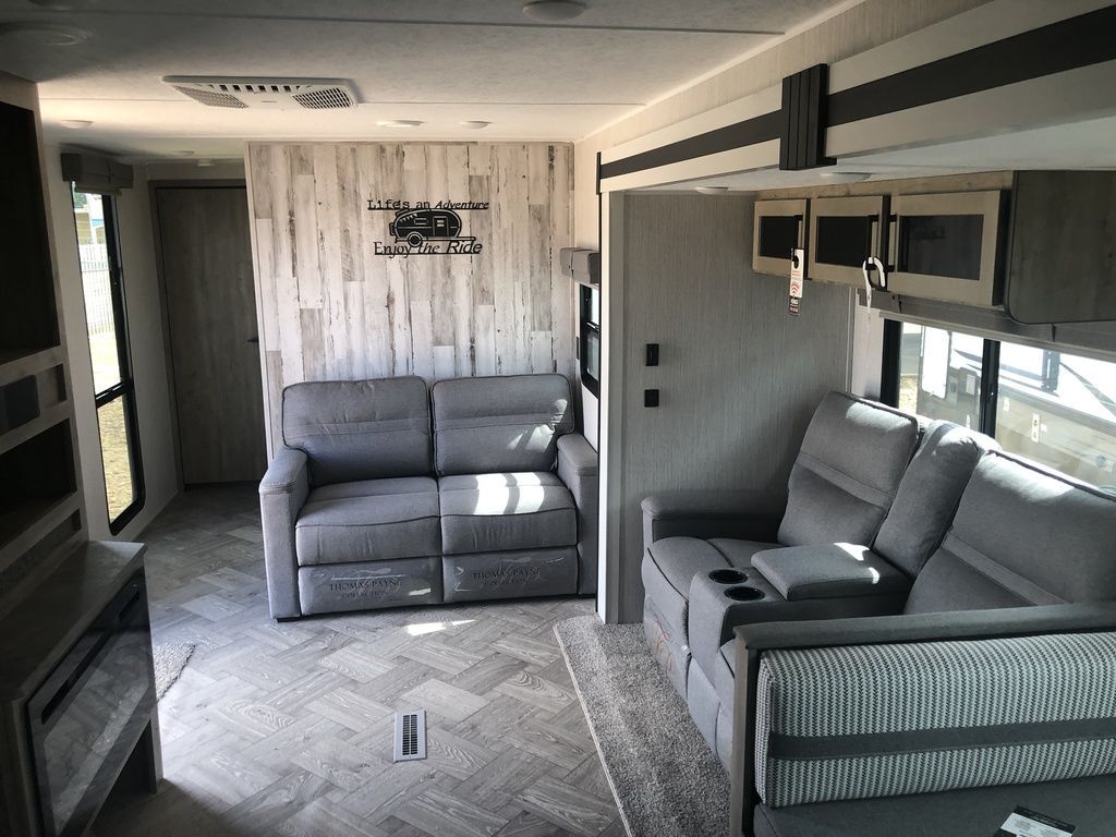 Living space with reclining chairs and overhead cabinets. 