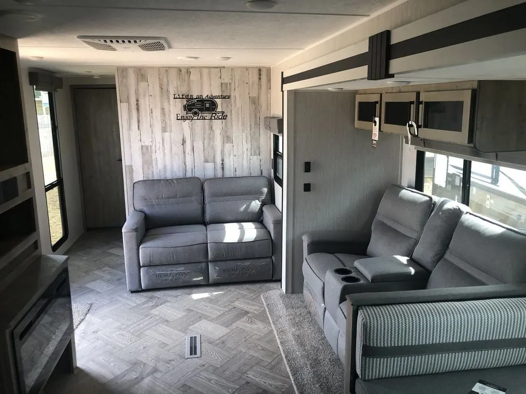 Living space with reclining chairs and overhead cabinets. 