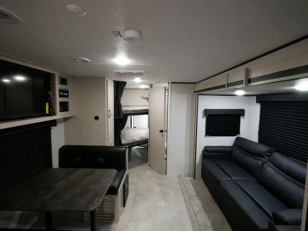 Interior view of the RV with a dinette, living space and a bedroom.