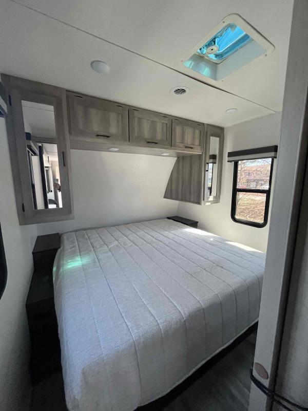 Bedroom with a queen size bed, overhead cabinets and shirt closets.