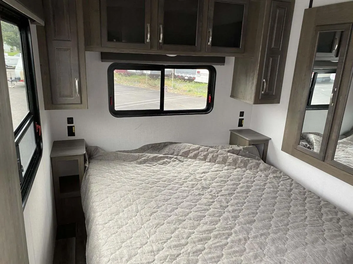 Bedroom with a queen size bed, overhead cabinets and shirt closets.