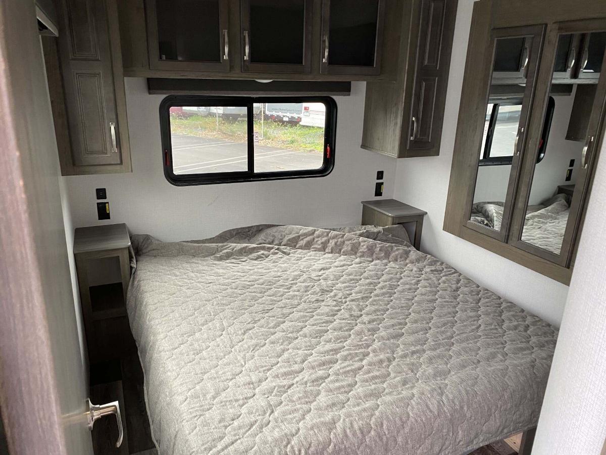 Bedroom with a queen size bed, overhead cabinets and shirt closets.