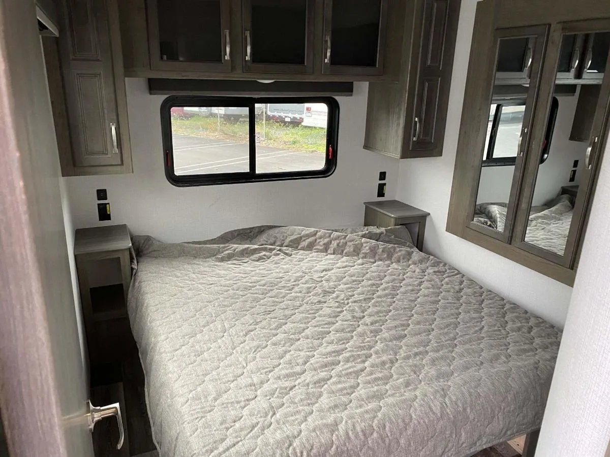 Bedroom with a queen size bed, overhead cabinets and shirt closets.