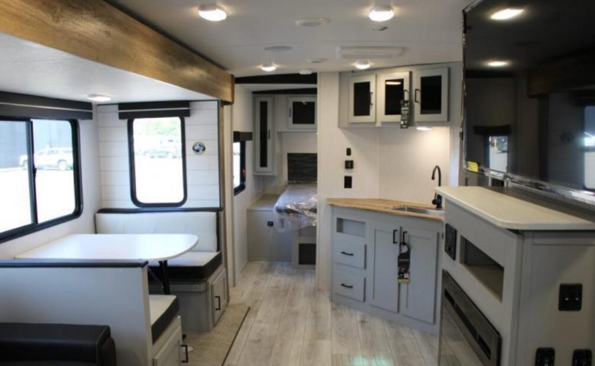 Interior view of the RV with a dinette, bedroom and a kitchen.