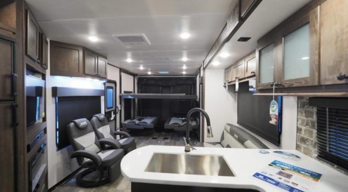 Interior view of the RV with a bedroom, living space and a kitchen.