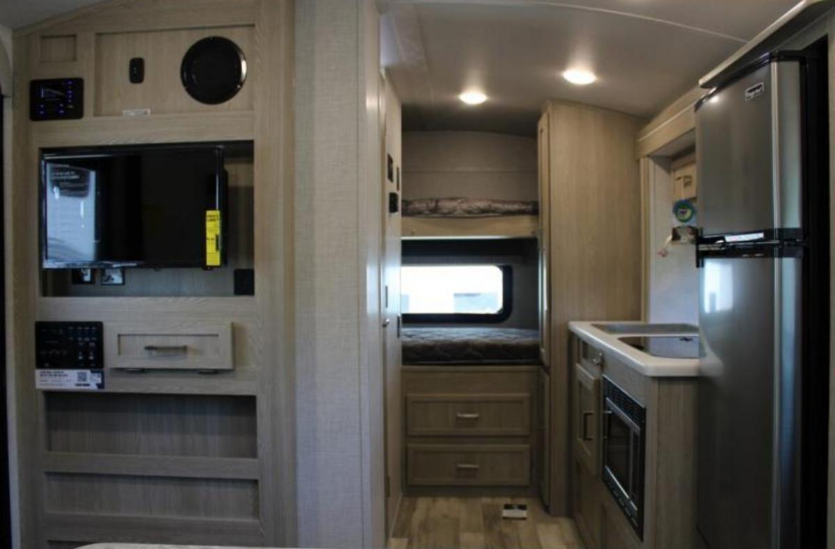 Interior view of the RV with an entertainment center, bedroom and a kitchen.