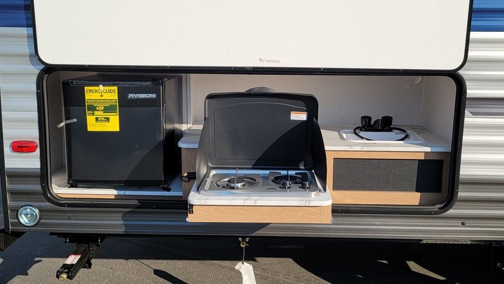 Outdoor kitchen with a gas burner, fridge and a sink.