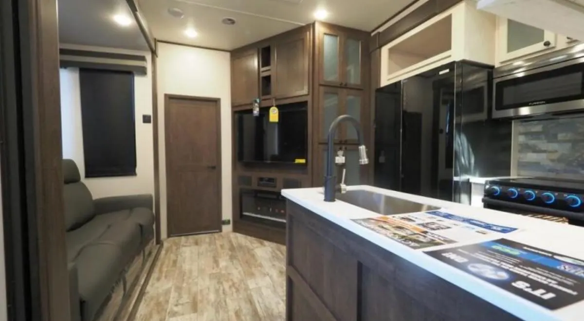 Interior view of the RV with a living space, entertainment center and a kitchen.