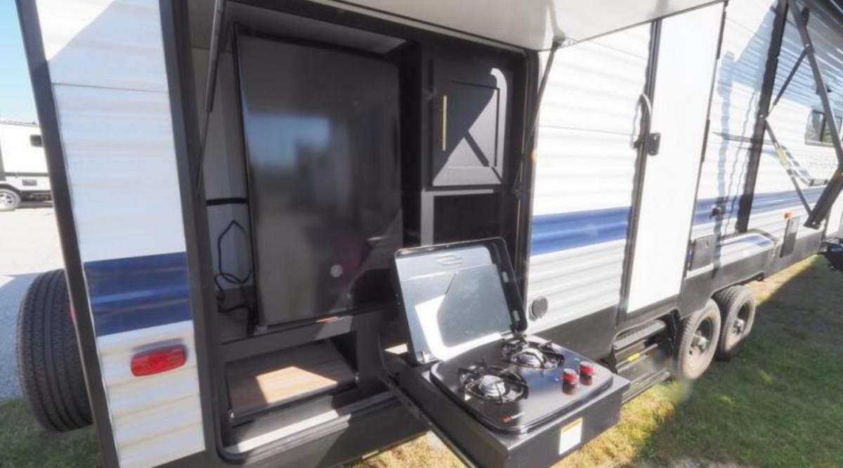 Outdoor kitchen with a gas griddle and a fridge.