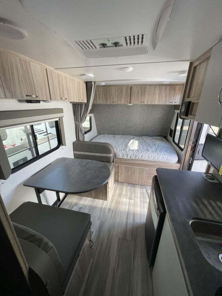 Interior view of the RV with a dinette, bedroom and a kitchen.