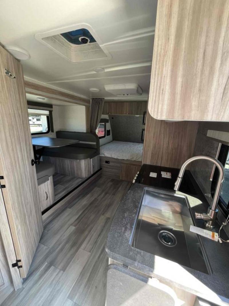 Interior view of the RV with a dinette, bedroom and a kitchen.