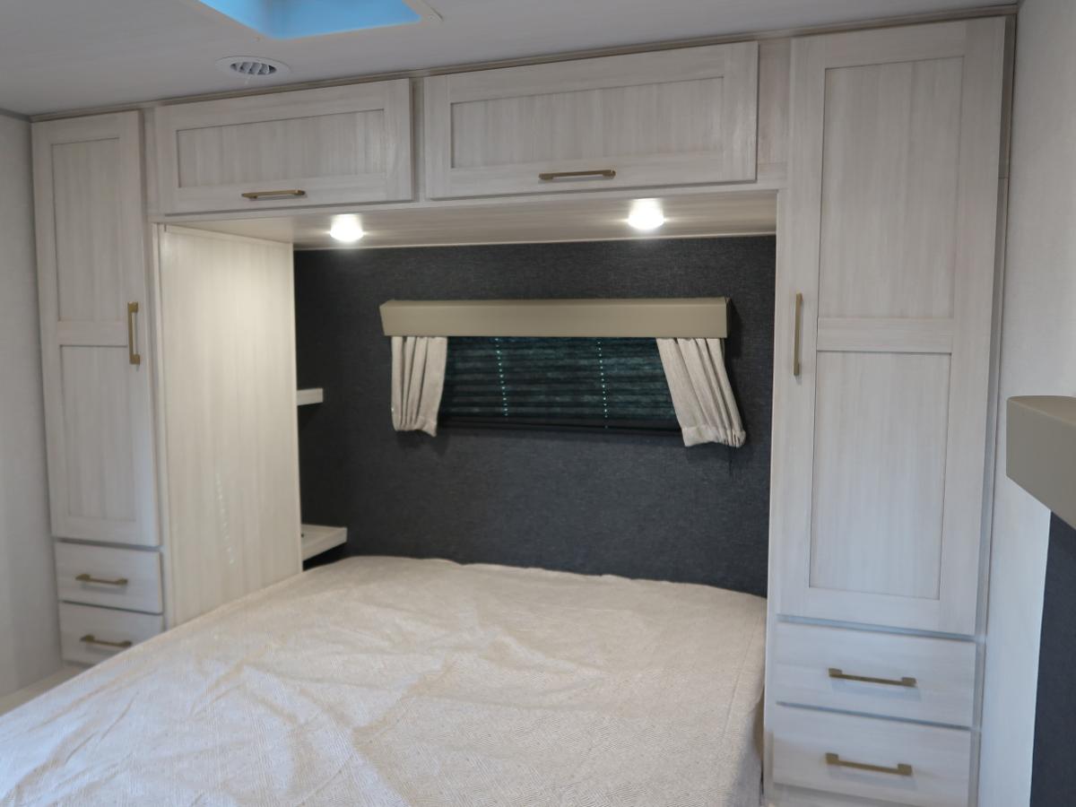 Bedroom with a queen size bed, overhead cabinets and shirt closets.