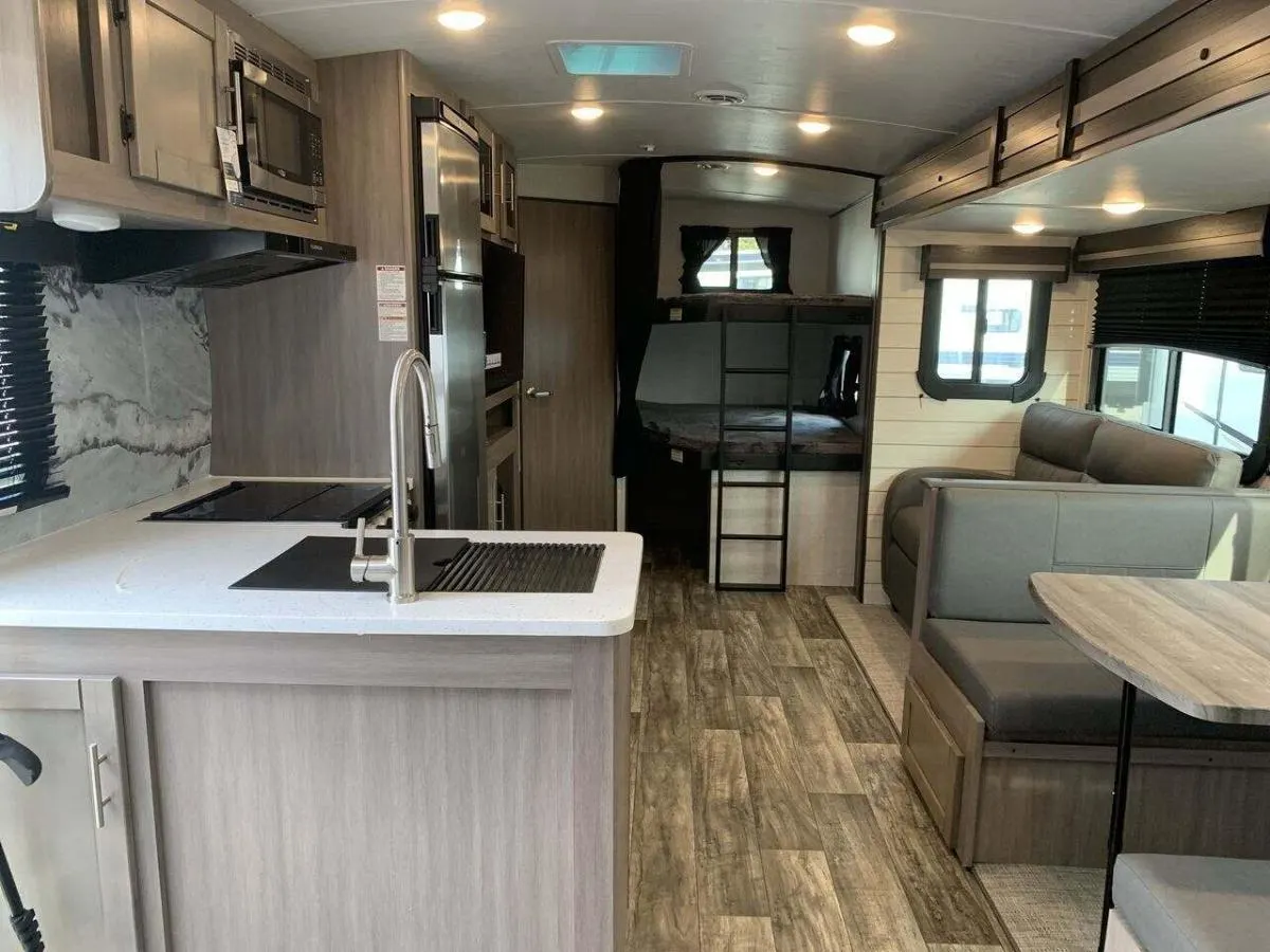 Interior view of the RV with a dinette, living space, bedroom and a kitchen.