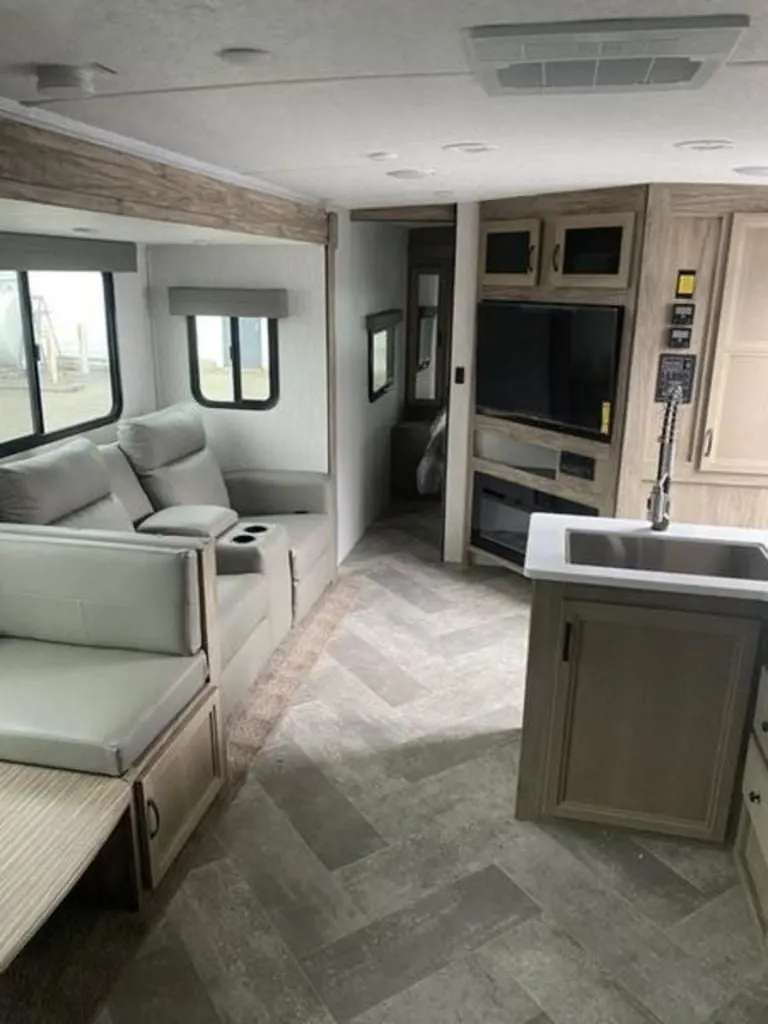 Interior view of the RV with a dinette, living space and a bedroom.