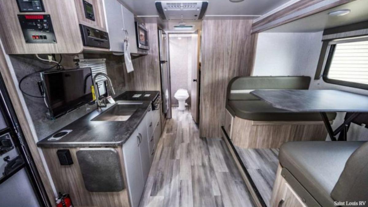 Interior view of the RV with a dinette, bathroom and a kitchen.