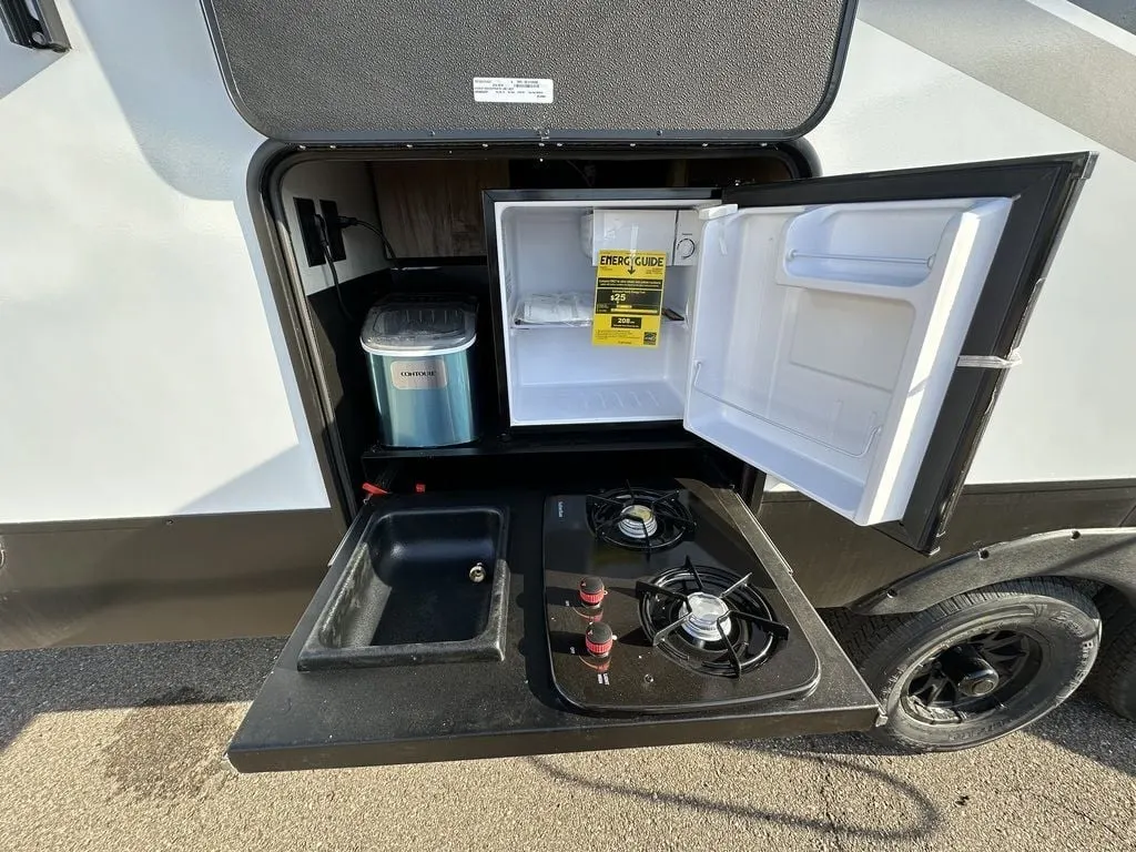 Outdoor kitchen with a gas griddle and a fridge.