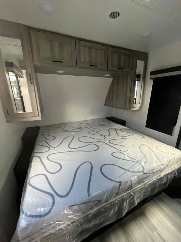 Bedroom with a queen size bed, overhead cabinets and shirt closets.