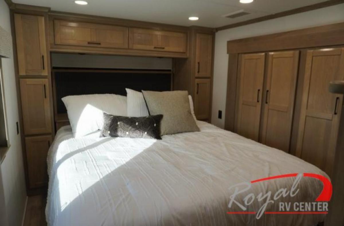 Bedroom with a queen size bed, overhead cabinets and closets.