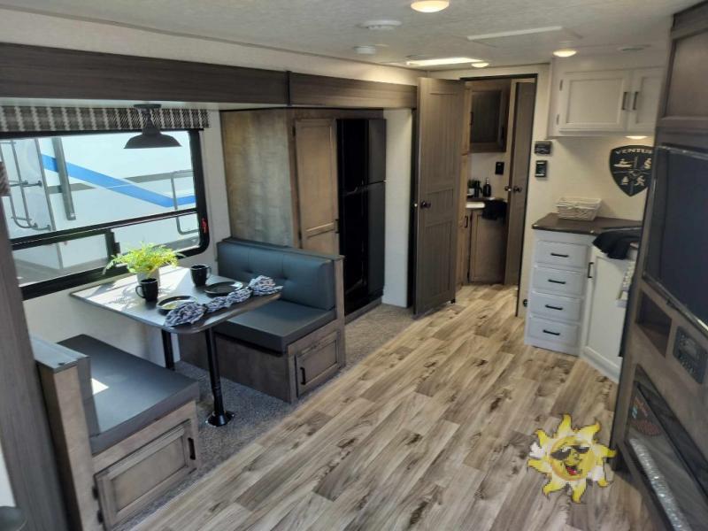 Interior view of the RV with a dinette, entertainment center and a kitchen.