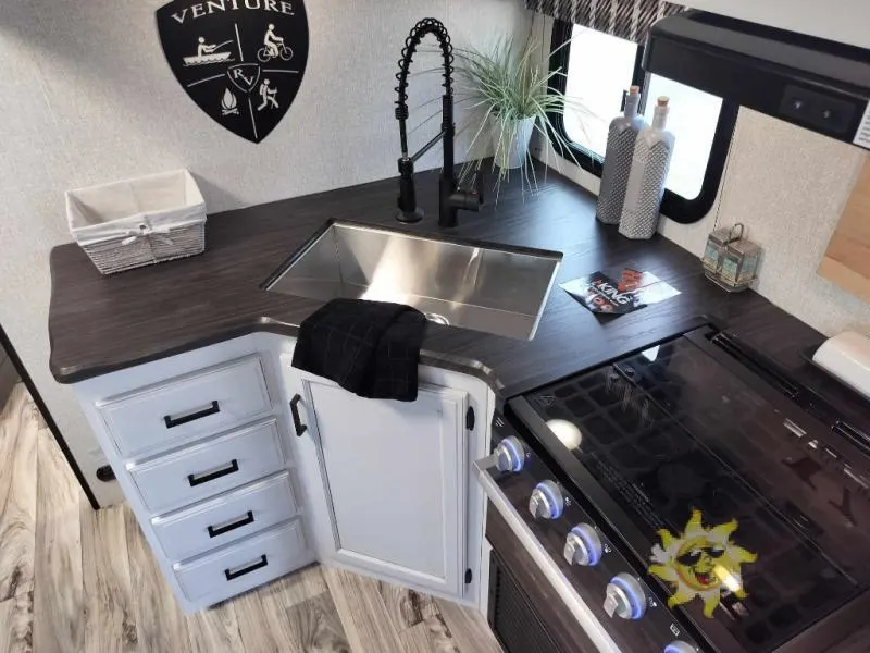 Kitchen with a gas range, sink and drawers.