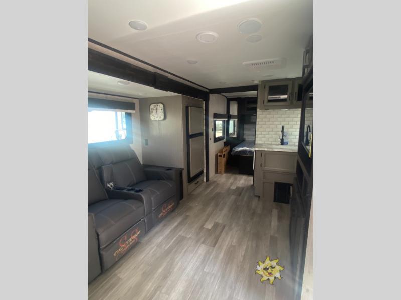 Interior view of the RV with a bedroom, living space and a kitchen.