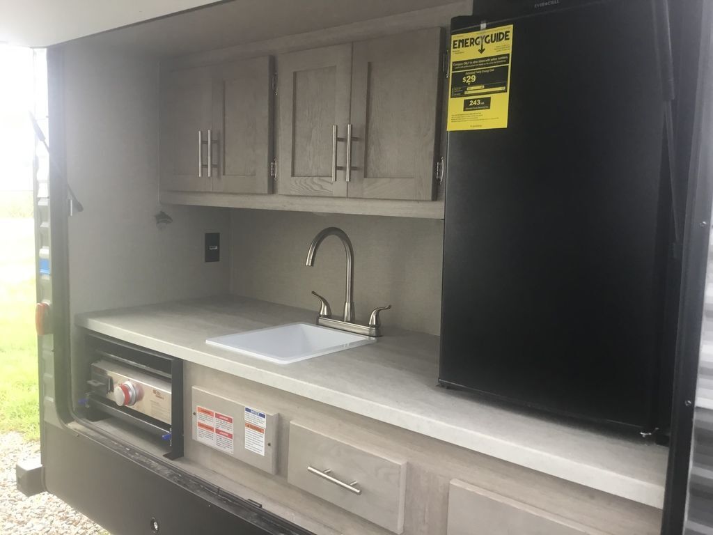 Outdoor kitchen with a gas griddle, sink and a fridge.