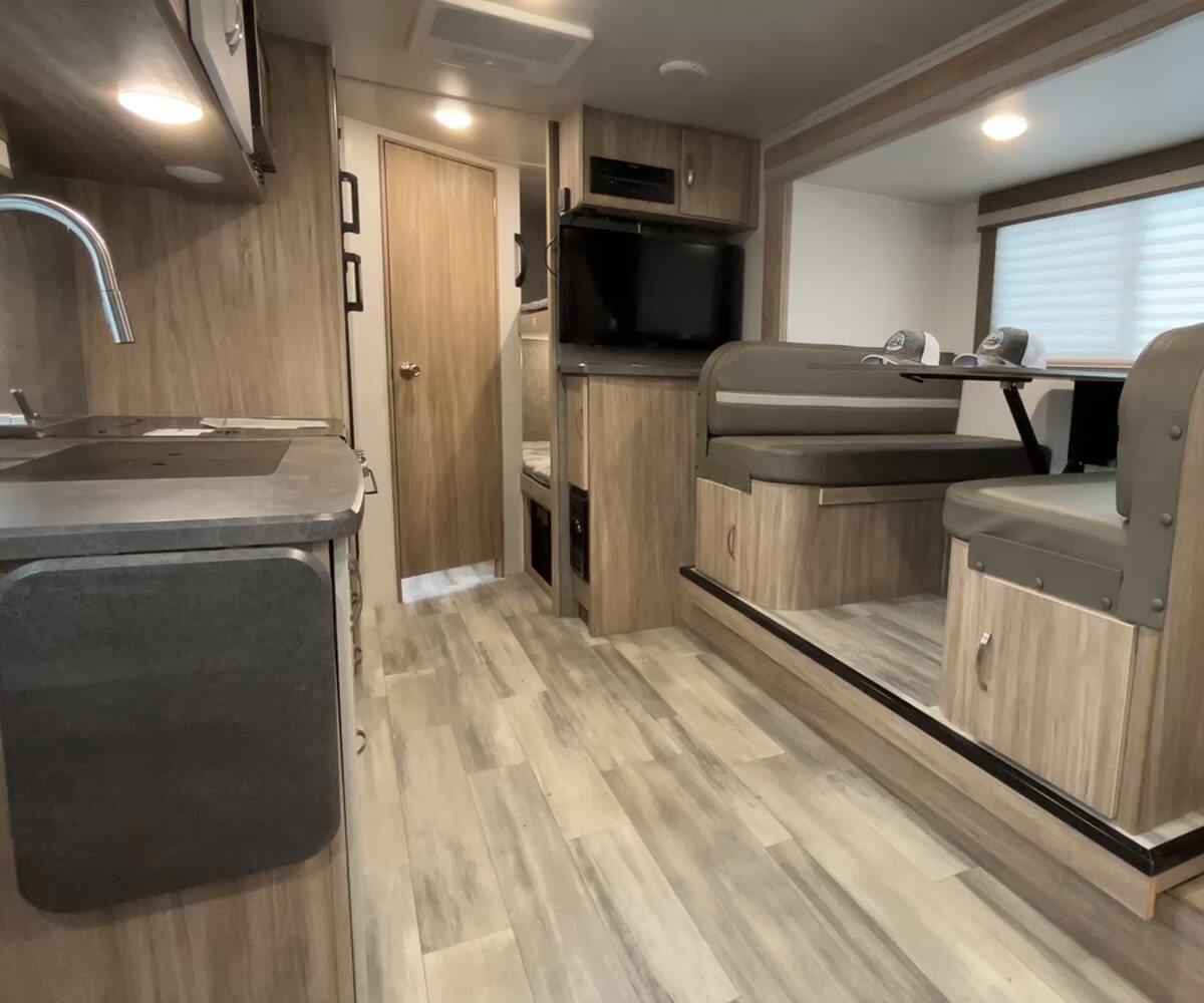 Interior view of the RV with a dinette, bedroom and a kitchen.